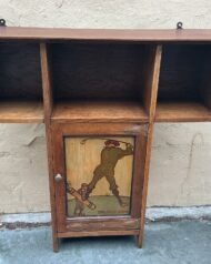 A solid oak wall cabinet, that would of original been made for smokers requisites. Made by Shapland and Petter in the Arts and Craft period circa 1900. It features a  picture of a Golfer with his caddie, done with beautifully stained wood and has the title "The first drive". It also has decorative arts and craft  copper hinges. Dimensions  Height 66 cm  Widest part 67 cm  cupboard 28 cm   Depth 18.5 cm